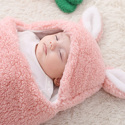 Newborn baby wrapped in pink fleece bunny swaddle blanket